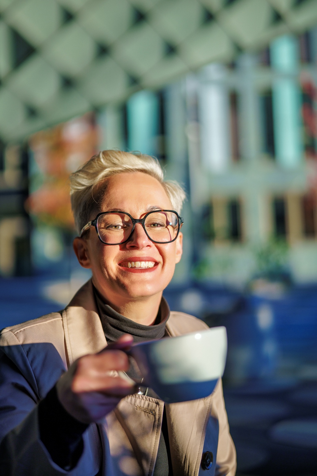Jenny Krause lacht in die Kamera und hält eine Tasse in der Hand.